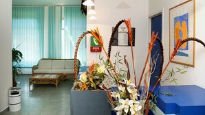 Un espace d’accueil avec un canapé, un comptoir bleu et des plantes décoratives.