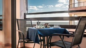 Un coin repas avec une table dressée pour deux personnes, offrant une vue sur la mer.