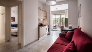 Un appartement moderne doté d’une cuisine, d’un coin repas et d’un canapé rouge.