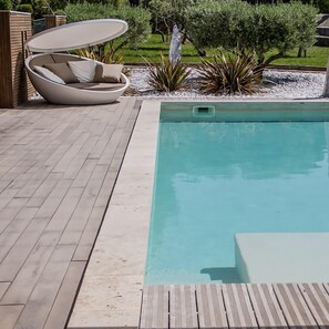 Una piscina al aire libre, sombrillas, sillones reclinables de piscina