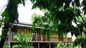 A two-story building with a balcony, surrounded by dense foliage. - The Last Frontier Boutique Resort			 (Kota Kinabatangan)