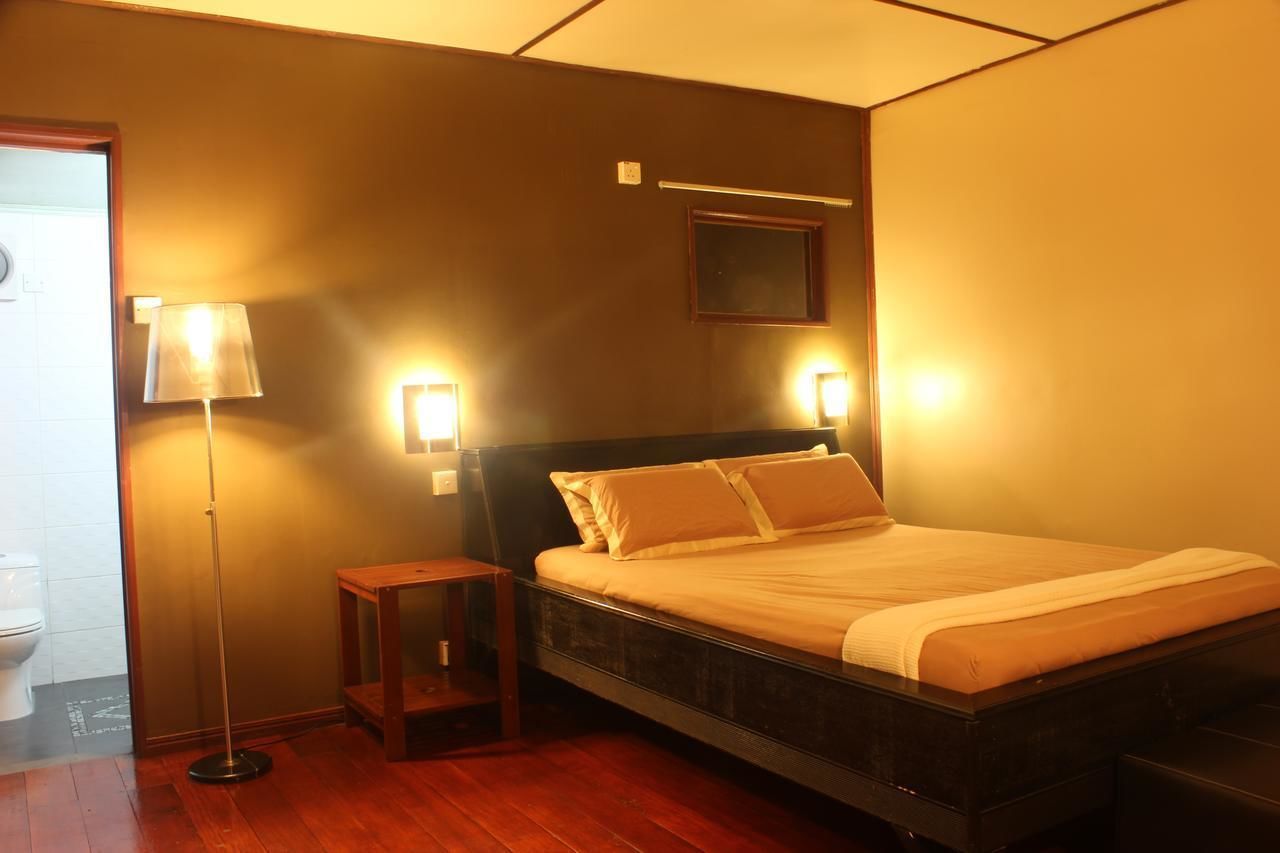 A hotel room with a bed, bedside table, lamp, and wall-mounted light fixture.