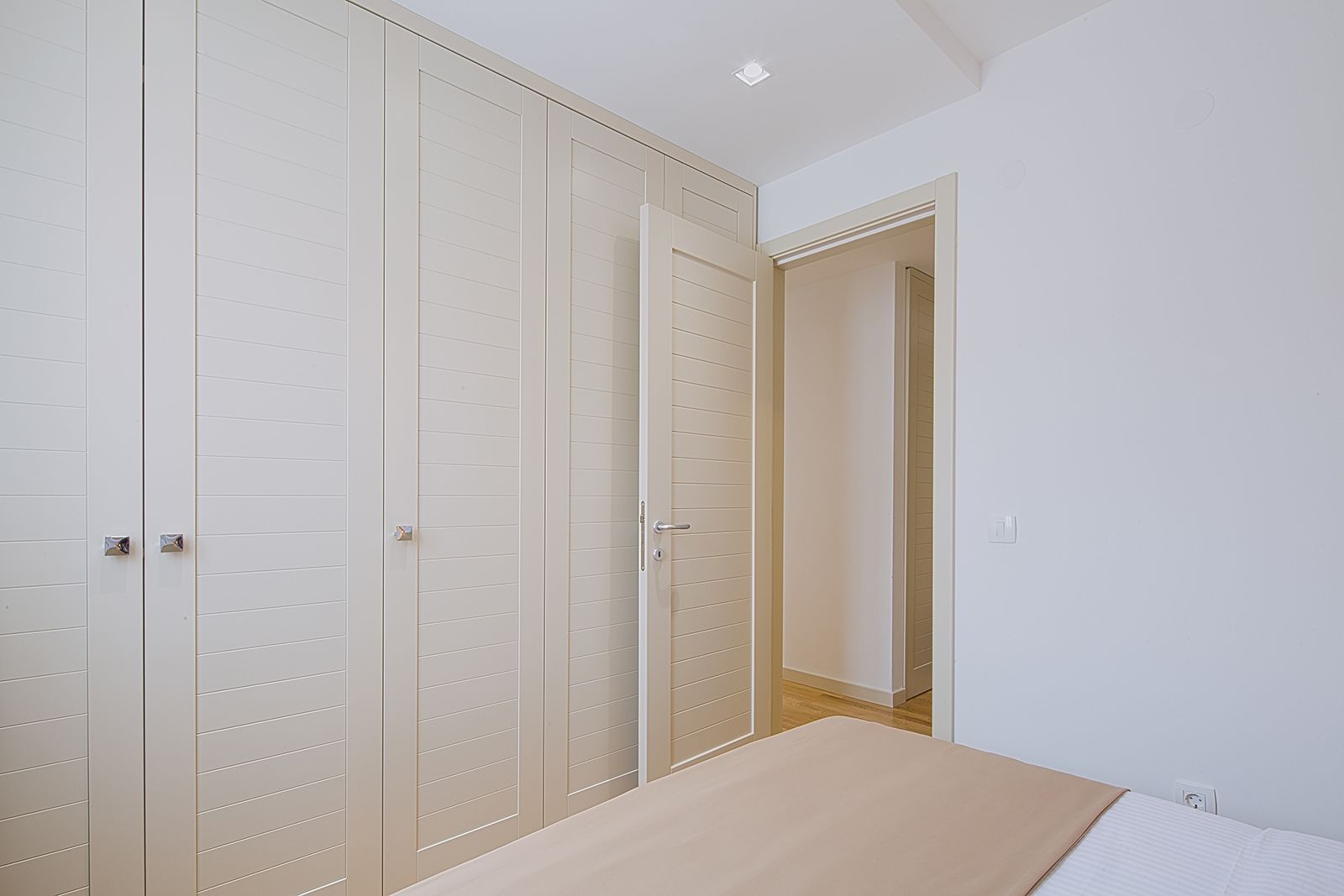 Een slaapkamer met een bed, een kledingkast en een deur naar een andere kamer.