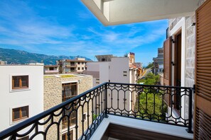 A balcony with a stone facade, a view of neighboring buildings, and a clear blue sky. - Spaska Apartments (Budva)