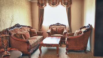 A traditional living room with ornate furniture, a patterned carpet, and a large window with curtains.