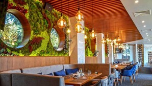 Un restaurante con pared verde, techo de madera y lámparas colgantes.