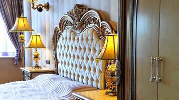 A luxurious bedroom with a tufted headboard, ornate lamps, and a large wardrobe.
