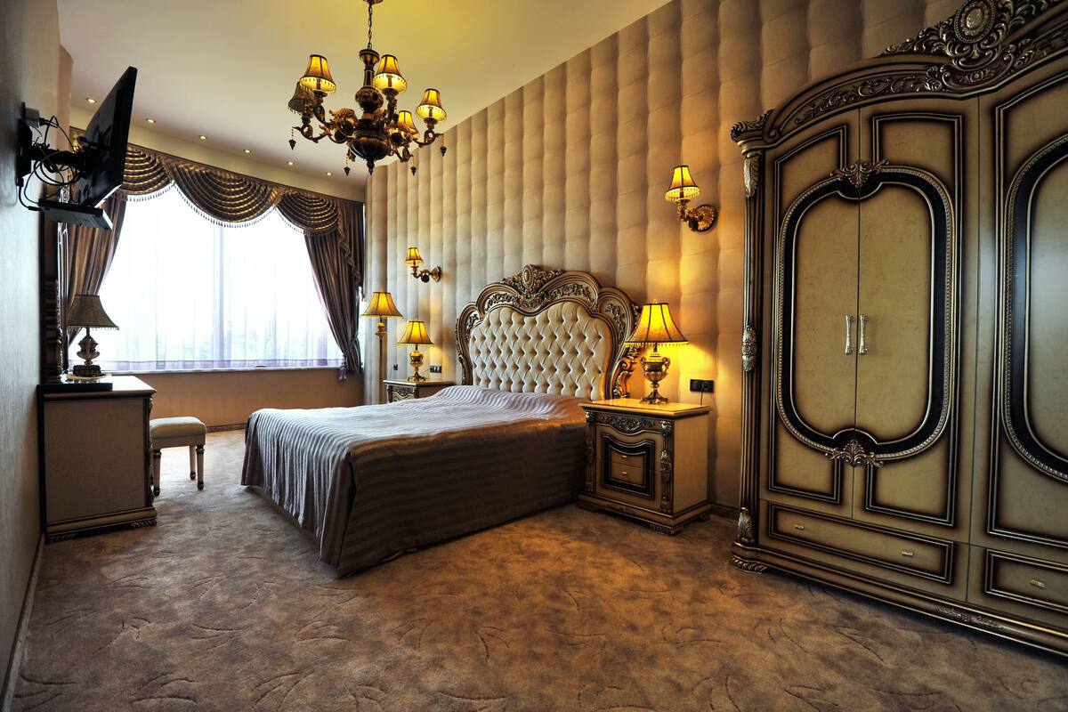 Une chambre à coucher avec un grand lit, une armoire, un lustre et un téléviseur.