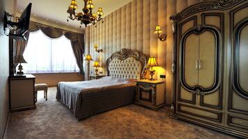A bedroom with a large bed, a wardrobe, a chandelier, and a television.