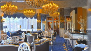 Un lobby de hotel lujoso con candelabros ornamentados, asientos cómodos y un suelo alfombrado azul.