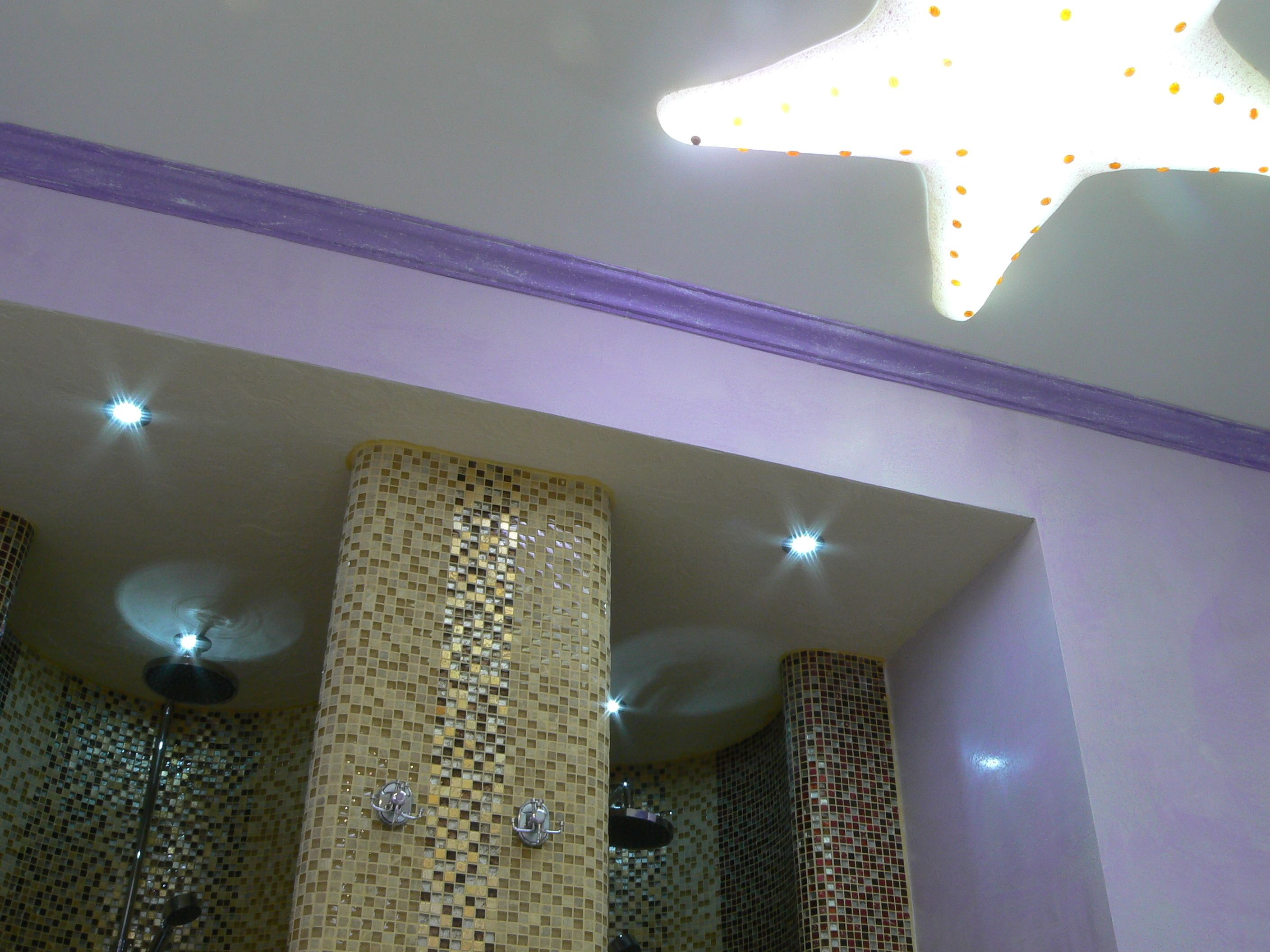 A bathroom with mosaic tile walls, a star-shaped light fixture, and a ceiling fan.