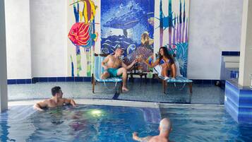 En swimmingpool med et muralmaleri, liggestole og flisegulv.