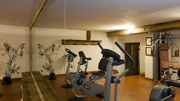 Une salle de sport équipée de matériel d’exercice, avec des poutres en bois et des plantes en pot.