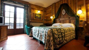 Dormitorio con paneles de madera, una cama, una silla, un escritorio y una ventana con cortinas.