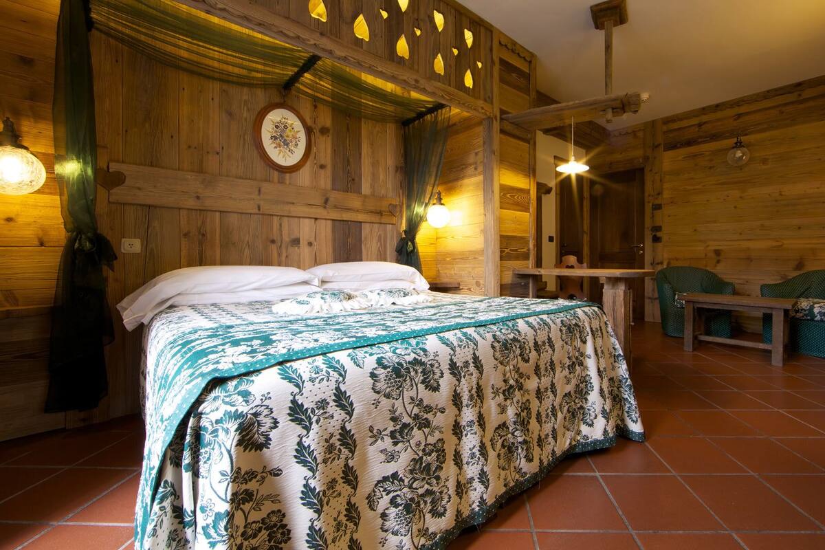 A wooden cabin-style bedroom with a bed, a small table, and two chairs.