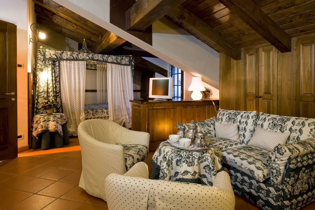 A cozy room with a bed, a sofa, a TV, and a lamp.