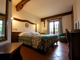 Un dormitorio con cama, una silla, un escritorio y una ventana con cortinas.