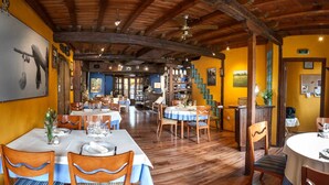 Een restaurant met houten balken, gele muren en gedekte tafels.