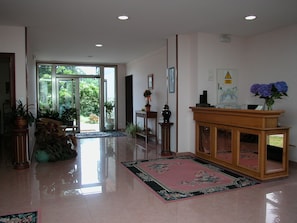 Eine geräumige Lobby mit einer großen Glasdoor, einem hölzernen Empfangsbereich und mehreren Kübelpflanzen.