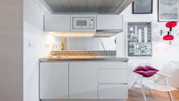 Una cocina moderna con armarios blancos, microondas integrado y un salpicadero decorado.