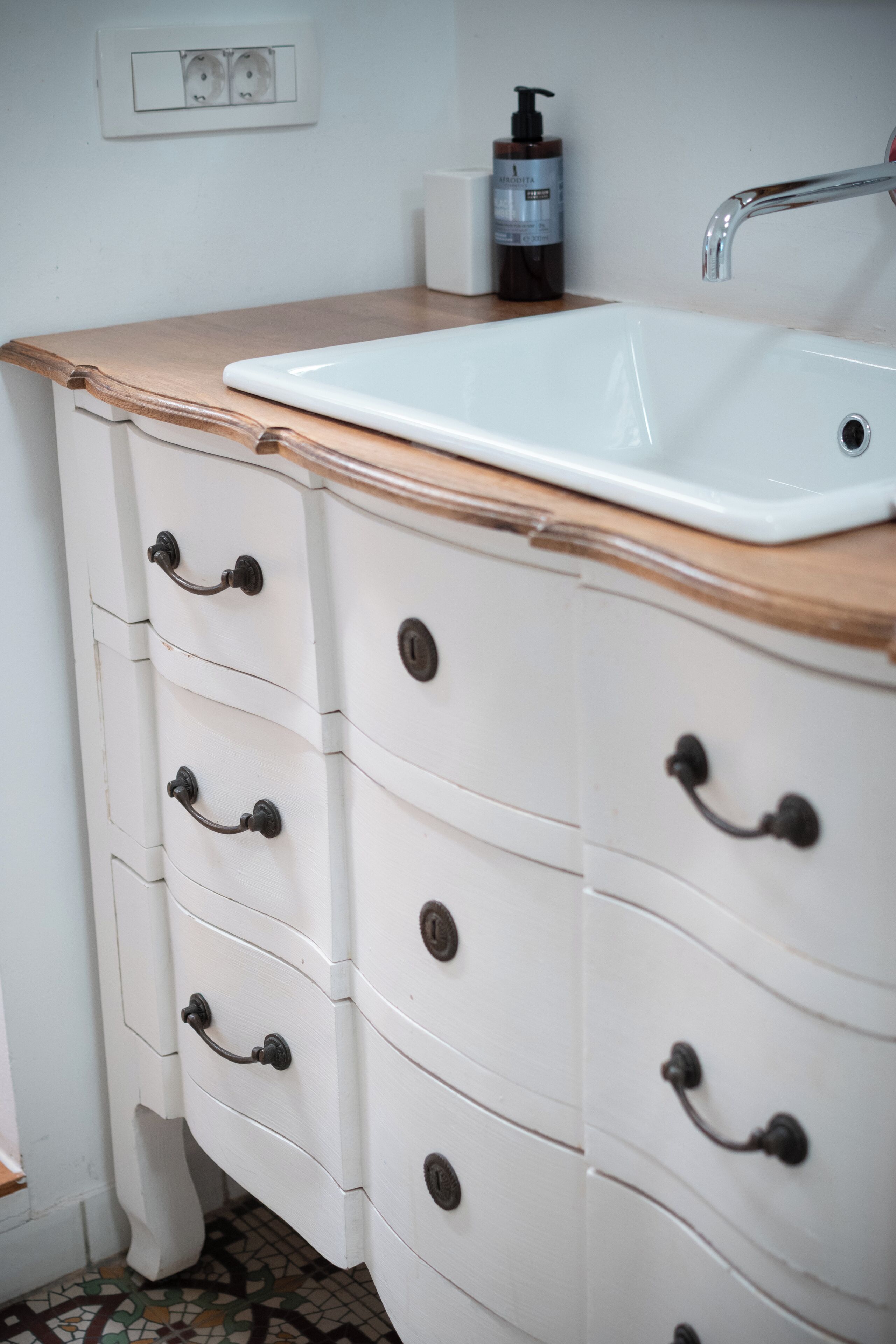 Een badkamer met een witte wastafel, een houten aanrecht en een witte wasbak.