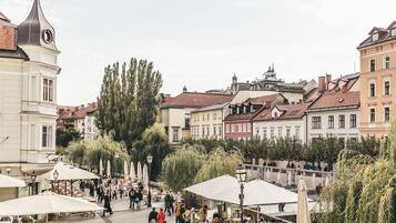 Un espace café animé en plein air, avec des tables et des parasols, entouré de bâtiments historiques aux styles architecturaux variés.