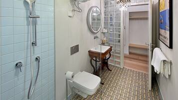 A bathroom with a shower, toilet, sink, and a mirror.