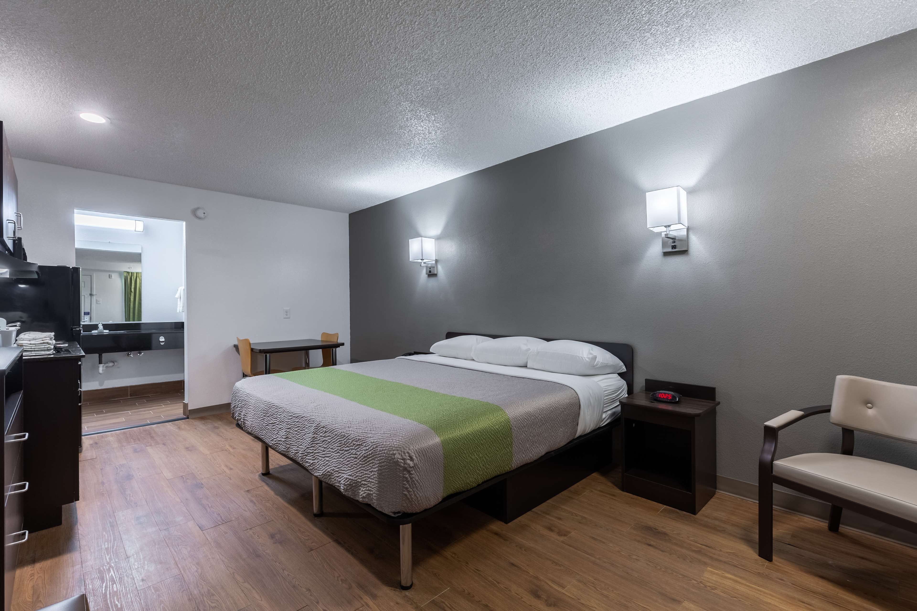 Une chambre comprenant un lit, des tables de chevet, une chaise et un coin cuisine.