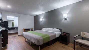 Une chambre comprenant un lit, des tables de chevet, une chaise et un coin cuisine.