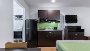 Una cocina compacta con microondas, refrigerador y televisor de pantalla plana.