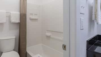 A bathroom with a toilet, a shower with a beige curtain, and a bathtub.