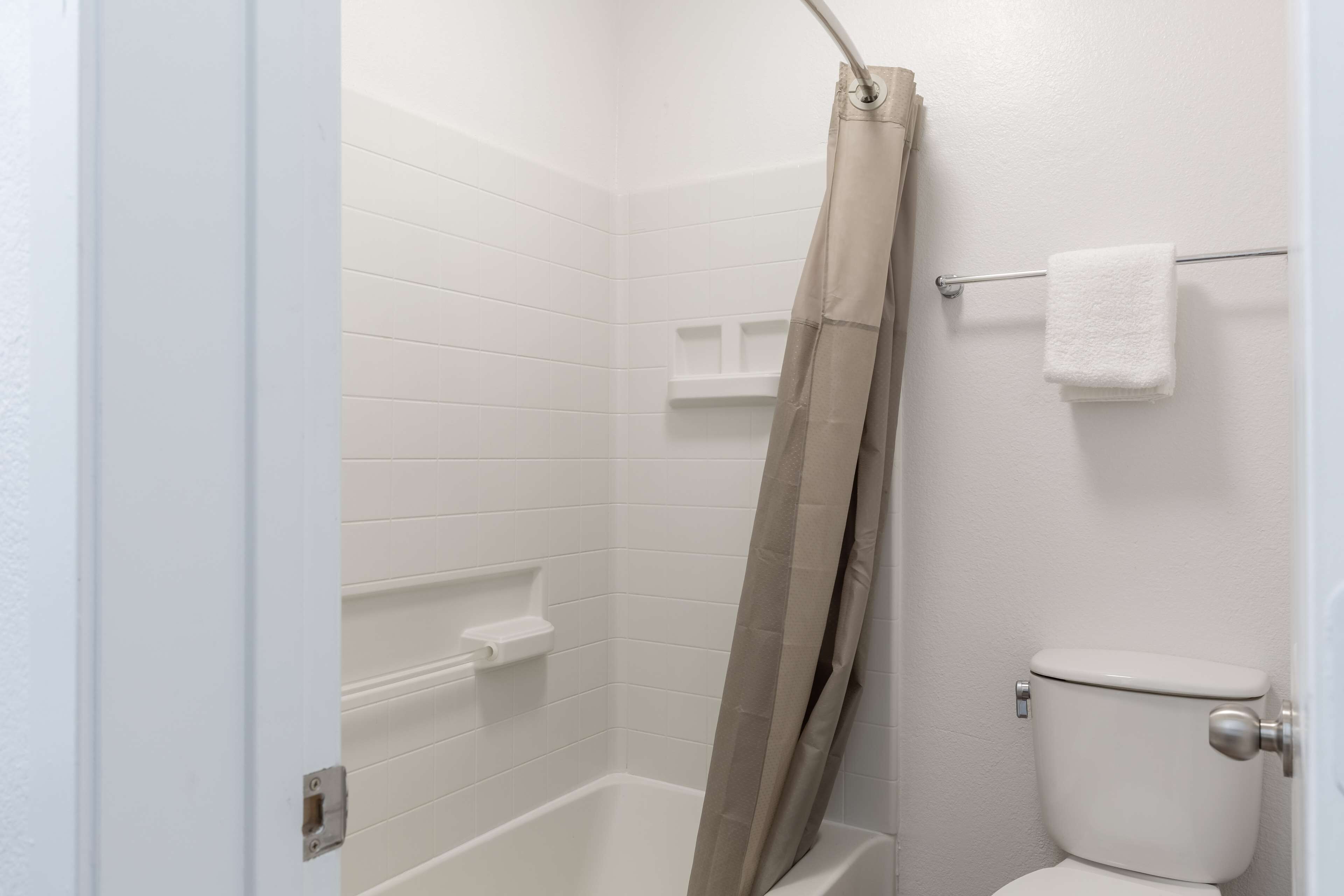 Un baño con cortina de ducha, inodoro y perchero para toallas.