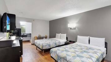 Une chambre d’hôtel avec deux lits, un bureau, une télévision et une kitchenette.