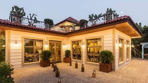 A two-story building with a tiled roof, large windows, and a gravel courtyard with lanterns. - Club Hotel Felicia Village - All Inclusive (Manavgat)