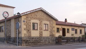 A stone building with a tiled roof, a sign indicating it is a local landmark, and a street lamp.