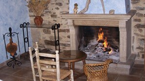 Una pared de piedra con una chimenea, una mesa y dos sillas en una habitación.
