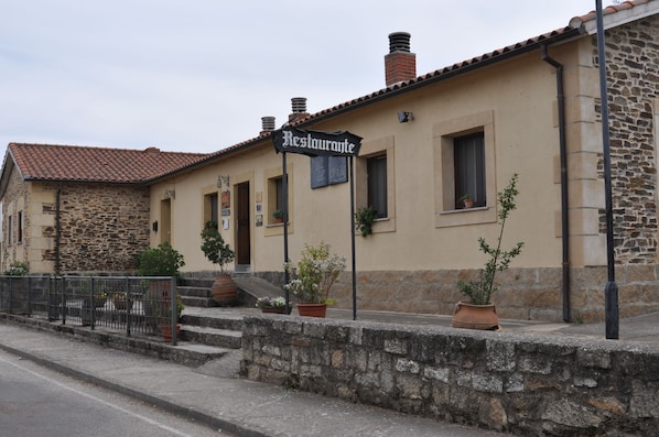 A building with a stone facade and a tiled roof, featuring a sign that reads "Restaurant."