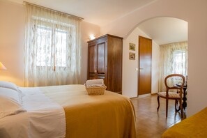 Ein Hotelzimmer mit Bett, Holzschrank, Stuhl und Schreibtisch.