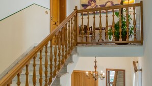A staircase with wooden balusters, a chandelier, a bench, and a patterned rug. - Agriturismo Il Quercione (Assisi)