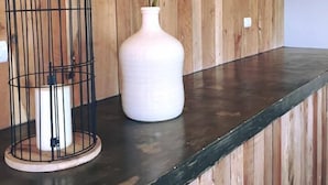 A wooden wall with a black metal cage and a white vase with yellow flowers on a dark countertop.