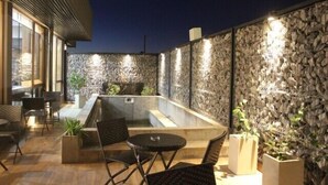 An outdoor patio area with a stone wall, seating, and a small pool.