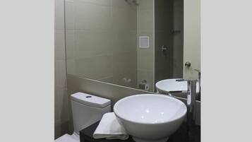 Un baño moderno con inodoro blanco, un lavabo grande y un espejo.