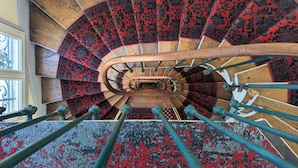 Una escalera de caracol con barandilla de madera y peldaños alfombrados.