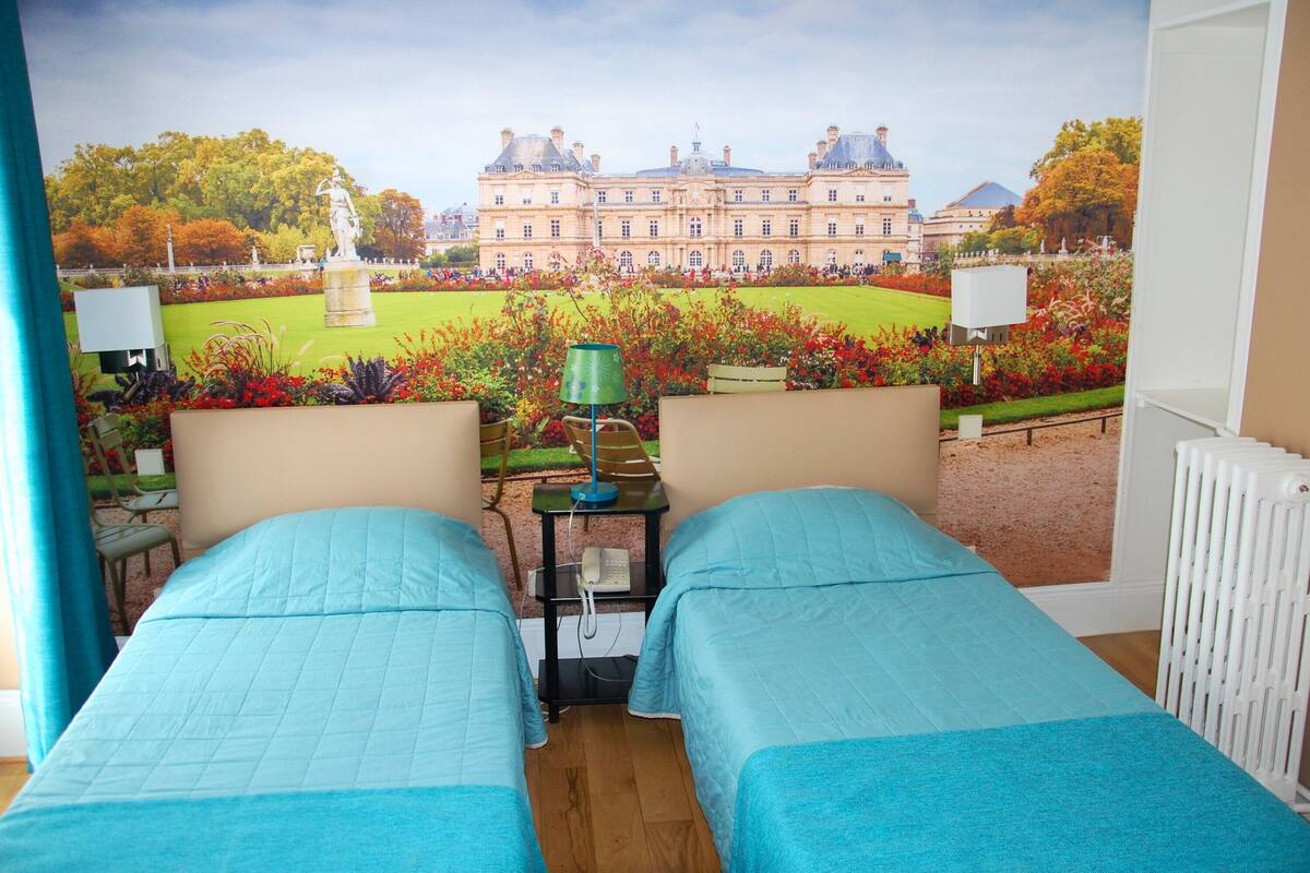 A room with two beds, a view of a large building, and a telephone on a side table.
