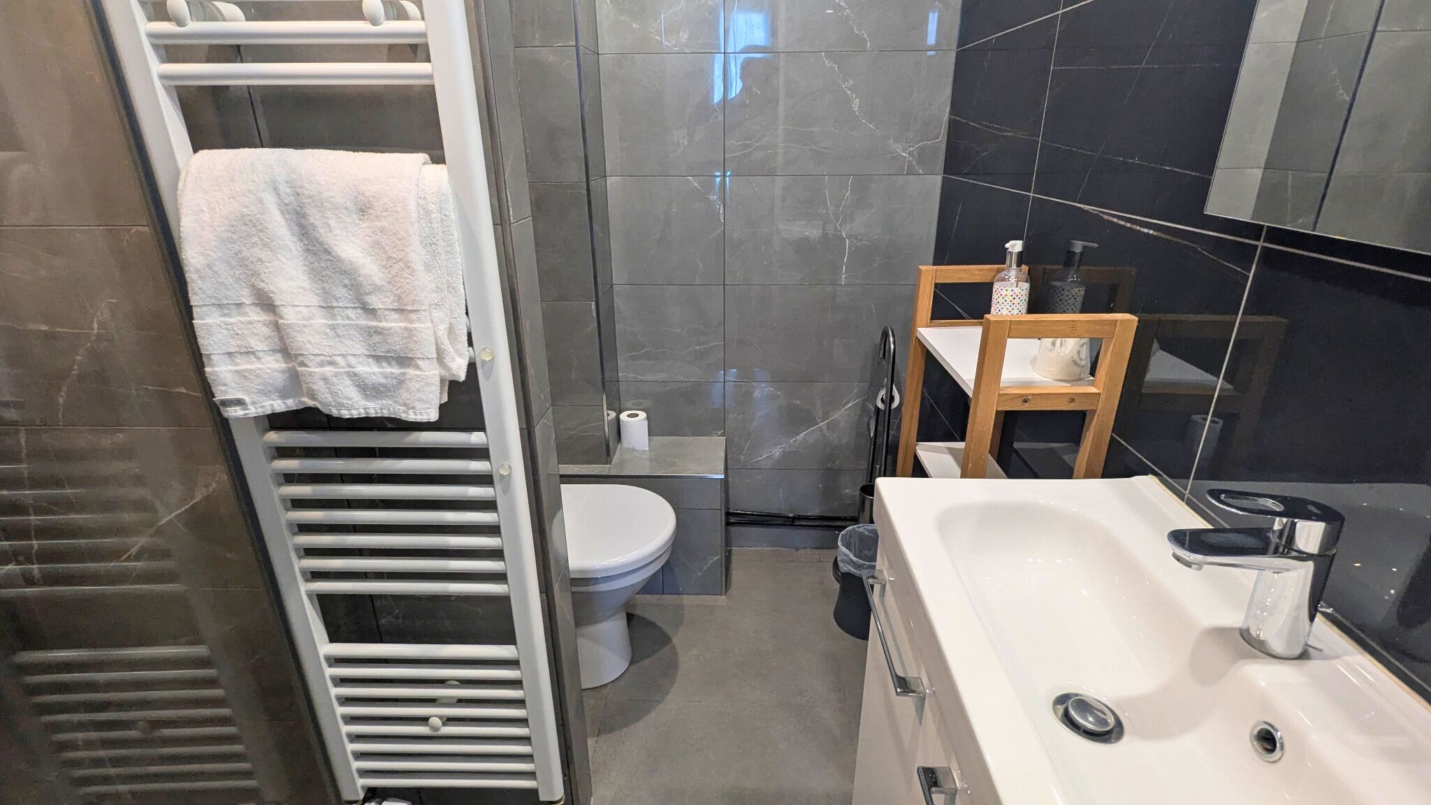 A bathroom with a white toilet, a sink, a mirror, and a towel rack.