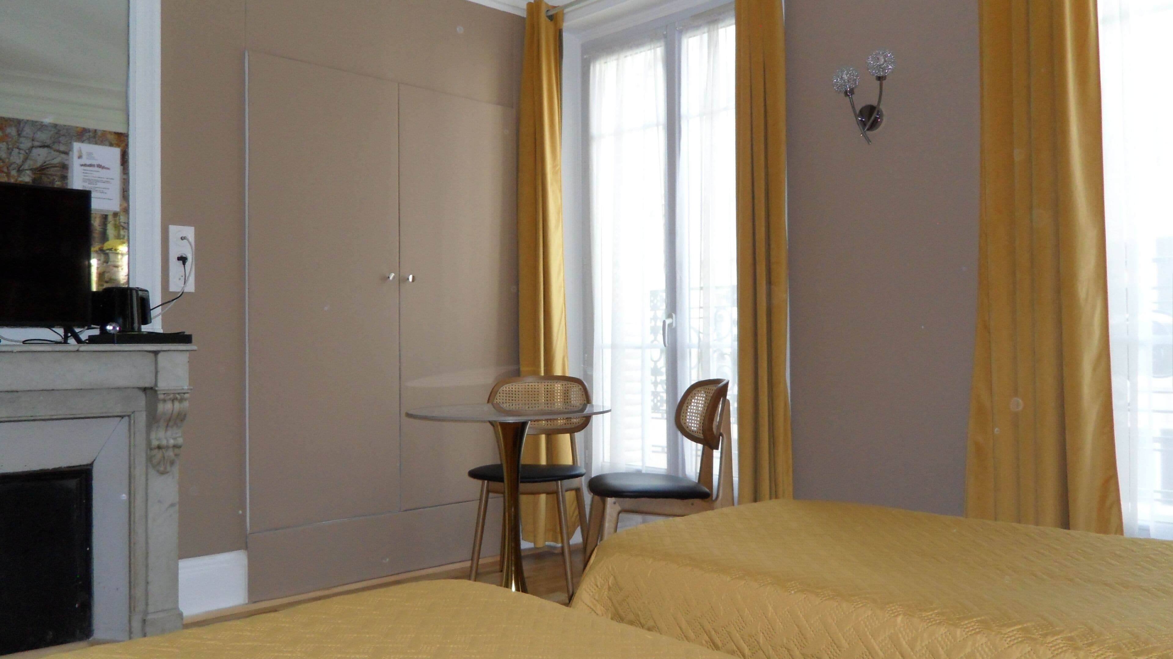 A hotel room with a bed, a small table, two chairs, a television, and a fireplace.