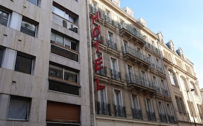 Um edifício com vários andares e um letreiro grande com a palavra 'HOTEL' na fachada.