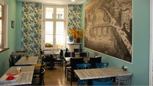 Un comedor con mesas y sillas, un ventanal grande y un mural en la pared.
