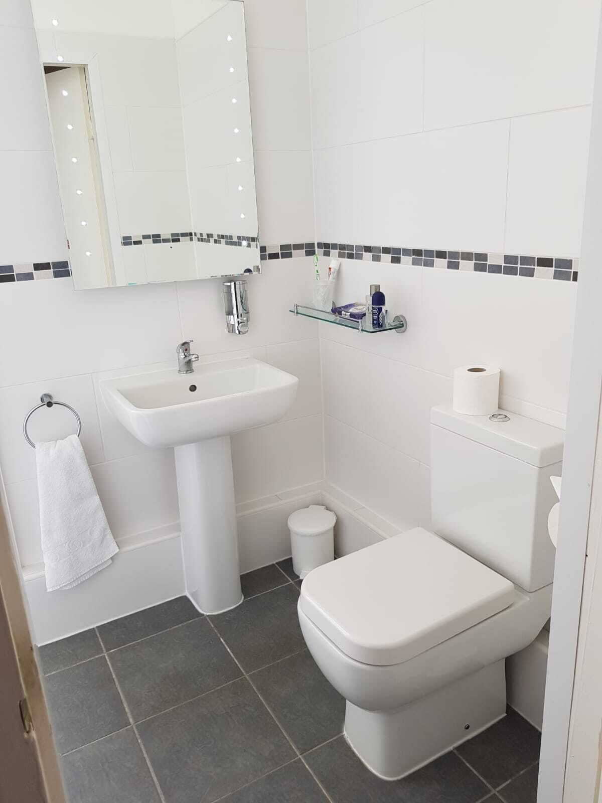 A bathroom with a white sink, mirror, and toilet.