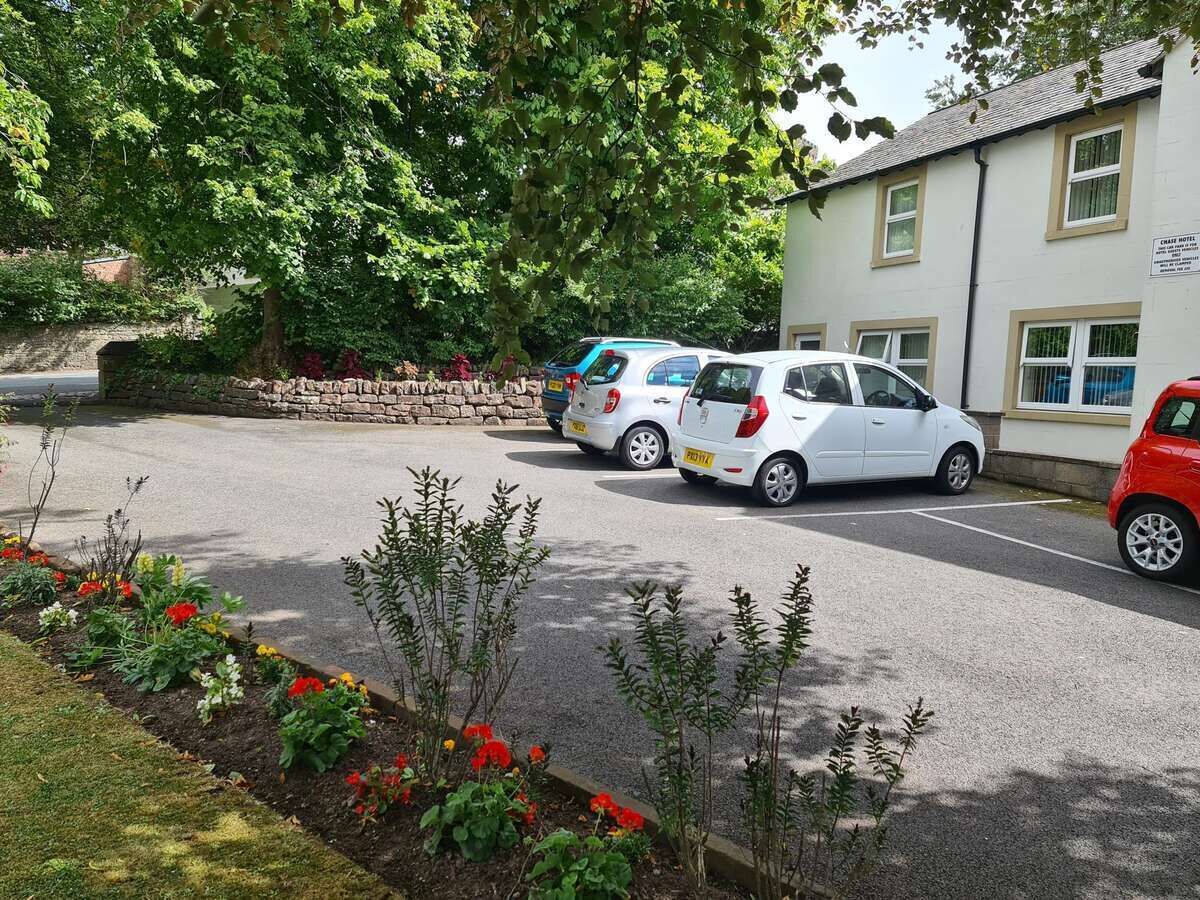A parking area with several cars, a stone wall, and a building labeled "Charr Hotel".